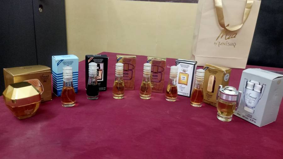A collection of Smart Collection perfume miniatures in various bottles and boxes, mostly new, displayed on a red surface.