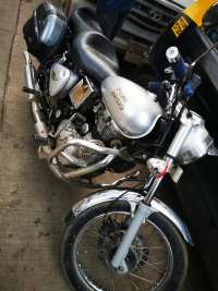 Silver Royal Enfield Bullet - Classic 350 motorcycle with black seat and side storage box, showing some wear.
